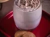 Foto da receita de cappuccino super cremoso  sobre uma louça vermelha em cima de uma mesa de madeira vista de cima