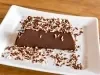 Imagem de um pedaço da sobremesa de chocolate coberta com chocolate granulado branco e preto sobre um prato.