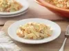 Imagem de um prato branco com a salada coleslaw de repolho. Ao lado um garfo e ao fundo mais um prato e uma travessa laranja.
