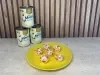 Prato amarelo com docinhos decorados com confeitos de coração vermelhos e brancos, com Leite Moça ao fundo.