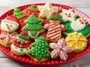 Em cima de uma mesa, prato redondo vermelho com biscoitos de estrelas, árvore de Natal, boneco de neve, decorado com glacê colorido.