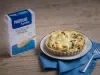 Foto da receita de quiche de aveia com espinafre servida em um grande prato desforme branco sobre um pano azul em cima de uma mesa de madeira