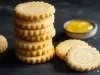 Em cima de uma mesa, biscoitos dourados e redondos com furos no meio.