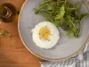 Imagem vista de cima de um prato cinza com um ovo feito no micro-ondas e uma salada verde ao lado.