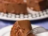Imagem de um prato branco com uma fatia de brigadeirão Moça com chocolate granulado e um grafo tirando um pedaço.