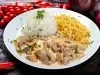 Imagem de um prato redondo branco com arroz, batata palha e strogonoff de carne cremoso. Ao fundo, cebolas e tomates cereja.
