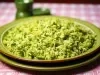 Em cima de uma mesa, prato redondo com porção de arroz soltinho verde e brócolis picados.