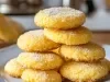 Em cima de uma mesa, prato redondo com biscoitos redondos suculentos, decorados com açúcar de confeiteiro.
