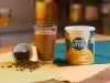 imagem mostra um copo de refresco de café cremoso, com coloração marrom e acabamento de canela