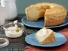 Imagem do bolo de polvilho com destaque para uma fatia do bolo com requeijão em cima em um prato azul claro.