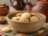 Em cima de uma mesa, tigela redonda com biscoitos redondos suculentos.