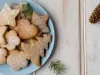 Em cima de uma mesa, prato redondo com biscoitos em formato de árvore de Natal, decorados com açúcar de confeiteiro.