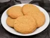 Em cima de uma mesa, prato redondo com porção de biscoitos redondo e dourados.
