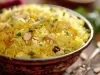 Em cima de uma mesa, tigela redonda com porção de arroz amarelo e soltinho com amêndoas picadas, decorado com salsinha picada.