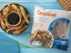 Foto da receita de Costelinha de Tilápia Copacol Empanada com Molho Oriental na Airfryer, servida em um tigela azul escura, com um pote pequeno com o molho no centro do prato, tudo numa bancada azul e com o pacote do produto Copacol