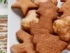 Em cima de uma mesa, prato com biscoitos em formato de estrelas e árvores de Natal.