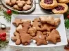 Em cima de uma mesa, prato com biscoitos em formato de estrelas e árvores de Natal.