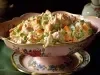Em cima de uma mesa, travessa com salada de maionese com cenoura, presunto e ervilha.