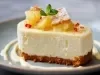 Fotografia de uma mini torta de abacaxi cortada na metade sobre um prato de tom azul com um creme branco decorando.