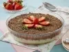Imagem de uma travessa redonda de vidro com o bombom de travessa decorado com raspas de chocolate e morangos.