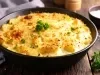 Em cima de uma mesa, refratário redondo com molho cremoso e queijo gratinado, decoado com florete de brocólis.