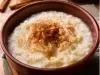Tigela redonda de porcelana marrom com arroz cremoso com canela em pó.