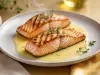 Filés de salmão grelhados servidos com molho cremoso claro e ervas, apresentados em prato raso com acabamento sofisticado.