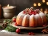 Fotografia de um bolo de Natal decorado, apresentado em um prato elegante. O bolo é polvilhado com açúcar de confeiteiro e adornado com pinhas e bagas vermelhas, cercado por ramos de pinheiro.