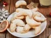 Em cima de uma mesa, prato branco com biscoitos em forma de meia lua, polvilhados com açúcar de confeiteiro.