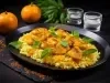 Em cima de uma mesa, prato redondo preto om arroz cremoso amarelo com pedaços de frango e decorado com folhas de hortelã.