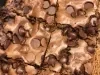 Brownie de chocolate cortado em quadrados, com gotas de chocolate na superfície e casquinha crocante.