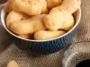 Em cima de uma mesa, tigela com biscoitos de polvilho crocantes e dourados.