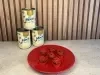 Docinhos de chocolate com granulado vermelho em forminhas vermelhas, dispostos em prato vermelho com Leite Moça ao fundo.