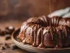 Fotografia de um bolo de chocolate em forma de bundt, coberto com chocolate derretido que escorre pelas laterais, posicionado em um prato escuro sobre uma superfície rústica.
