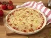 Imagem de uma pizza redonda de queijo muçarela com um paninho listrado vermelho e branco do lado e tomates.