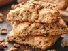 Em cima de uma mesa, pedaços de biscoitos de nozes picadas enfileirados em cima do outro.