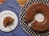 Imagem de um brigadeirão coberto com chocolate granulado e uma fatia em um prato branco.