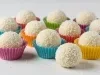 Imagem de diversos beijinhos enrolados no coco ralado sobre forminhas coloridas.