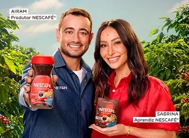 Produtor Airam e aprendiz Sabrina Sato Nescafé segurando potes de café em plantação, em campanha da Vila Nestlé.	