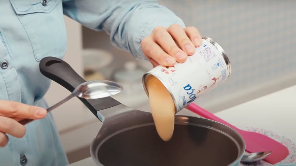 Manual do Bolo Perfeito: uma pessoa colocando leite moça na panela