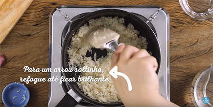 Pessoa mexe o arroz na panela usando uma espátula