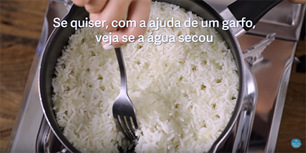 Pessoa mexe arroz na panela com garfo